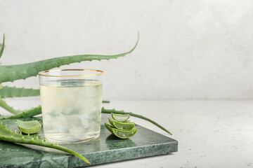 Board with glass of aloe juice and leaves on white background - Powered by Adobe