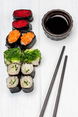 Set of sushi and soy sauce in a bowl, chopsticks.