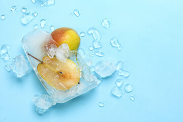 Fresh pear frozen in ice on blue background