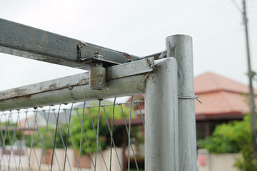 Rusty metal guide bracket with bearing rollers for sliding gate.