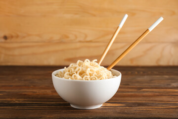 Bowl with tasty noodles on wooden background