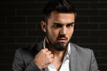 Bearded businessman adjusting collar on dark background
