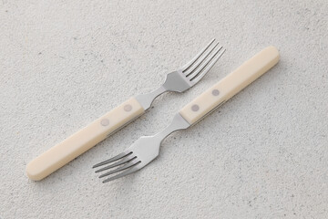 Stylish stainless steel forks on light background