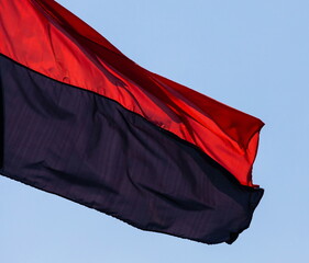 Fototapeta Red-black flag of the Right Sector in Ukraine, isolated against the blue sky, close-up. Background of the silk fabric fluttering in air obraz