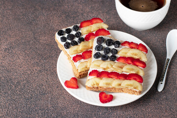 American flag sandwiches with fruit and cream cheese on rye bread and a cup of coffee. Independence Day breakfast idea