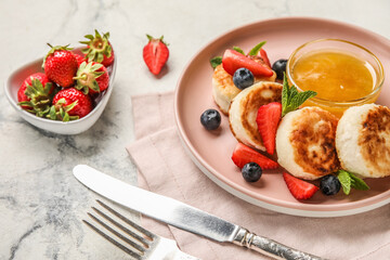 Plate with delicious cottage cheese pancakes, berries and honey served on light background
