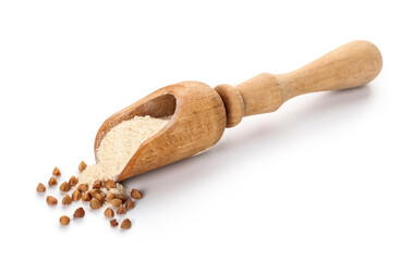 Scoop with flour and buckwheat grains on white background