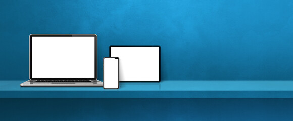 Laptop, mobile phone and digital tablet pc on blue wall shelf. Banner background