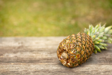 Pineapple is lying on a wooden surface. Wooden background