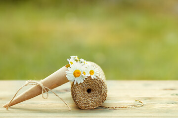Bouquet of daisies and a coil of rope on a wooden floor in the garden.