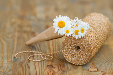 Bouquet of daisies and a coil of rope on a wooden floor in the garden.