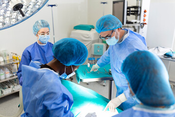 Surgeon team in uniform performs an operation on a patient at a cardiac surgery clinic. Modern...