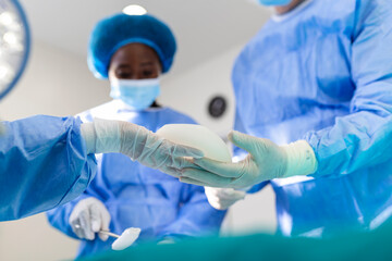Doctor holding silicone implant medical. Surgent hold silicone implant and install in woman bust...