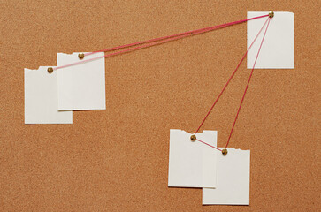 Blank paper notes are pinned to a cork board. The concept of detective investigation. Copy space.