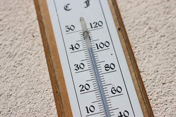 Summer heat, high temperature outdoors. Thermometer reaching 40 degrees Celsius scale on a white wall background