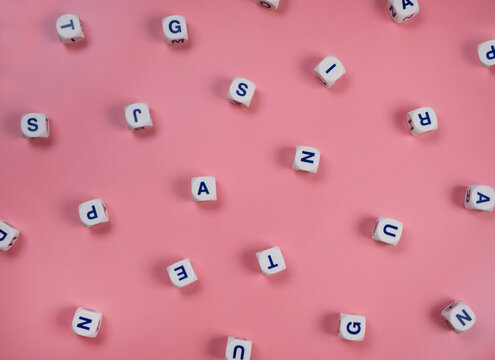 cubes or blocks word with letters randomly on a pink background - the concept of a newborn girl , school education or self education 
