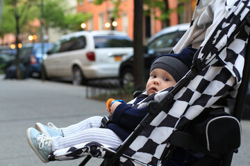 Little beautiful boy in a stroller on the street	
