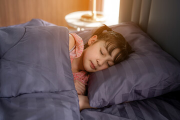 Child little girl sleeps in the bed with a doll.