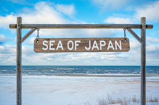 Wooden sign with sea of Japan text against sea, blue sky and beach.