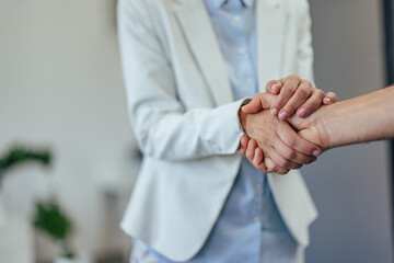 Focus on the people doing a handshake, a female dressed in a bright suit.