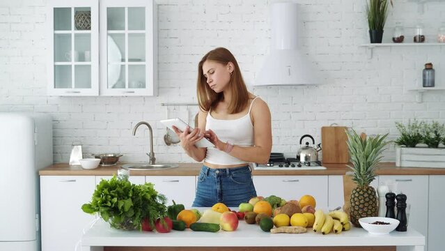 Young blogger woman preparing food, taking pictures on phone tablet for her social accounts or video stories. Weight loss and diet.