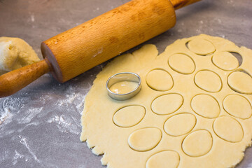 Raw dough biscuits in the shape of an egg and a rolling pin, preparing for the holiday homemade baked goods from natural products, selective focus