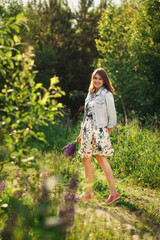 Beautiful smiling young millennial woman in casual clothes with a bouquet of lupins enjoying summer.