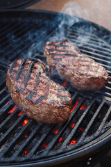Barbecue dry aged wagyu roast beef steak grilled as close-up on a charcoal grill with fire and smoke