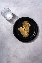Banana Cake on black plate with mineral water for dessert.