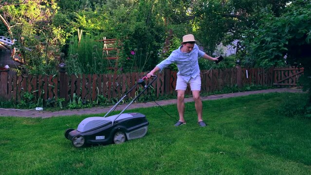 Young man dance in the garden with lawn mower