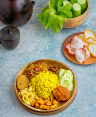 Indonesian yellow rice served with balado eggs, tempeh orek, vermicelli, potato fried chili sauce, where yellow rice is a typical breakfast menu for Southeast Asian people, especially Indonesia.