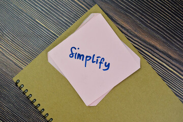 Concept of Simplify Reminder write on sticky notes isolated on Wooden Table.