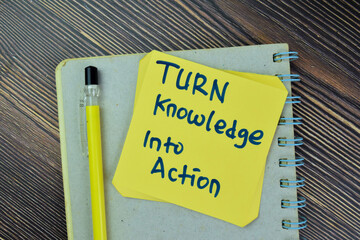 Concept of Turn Knowledge Into Action write on sticky notes isolated on Wooden Table.