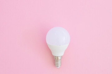 LED light bulb lies on a pastel pink background. Energy saving concept. Minimalism, top view