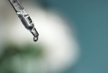 Pipette with transparent fluid hyaluronic acid or serum. Cosmetics, science and healthcare concept closeup. Dose of serum or retinol falls in a bottle. Front view. Beauty product presentation, macro