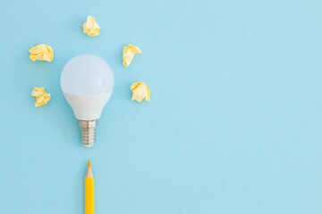 LED lamp and pencil lies on a pastel blue background. Nearby - pieces of satin yellow ribbon...