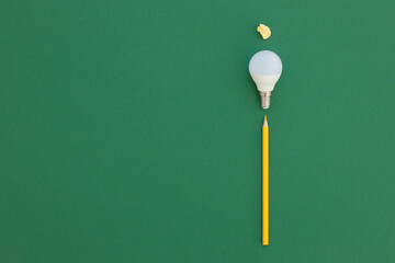 LED light bulb lies on a pastel green background. Energy saving concept. Minimalism, top view