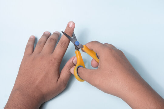 a man's hand is trying to cut a finger using scissors