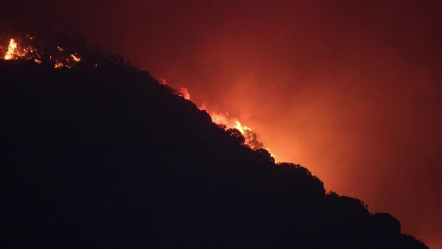 Flames from wildfire burning in Utah climbing up mountainside after it started from target shooters.
