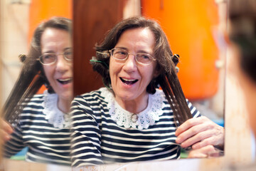 Senior Woman Comb Her Hairs in the Mirror of Home Bathroom