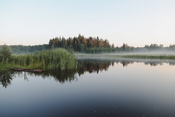 summer evening twilight view on picturesque plain lake surface with reflections of sky and trees
