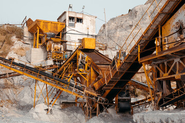 Quarry machines and piles of gravel over blue sky. Stone crushing and screening plant