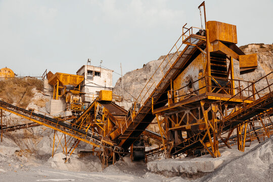 Quarry machines and piles of gravel over blue sky. Stone crushing and screening plant