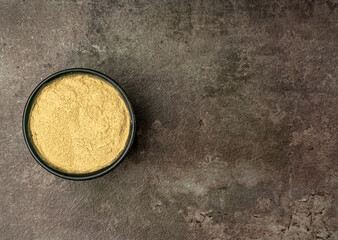 Aromatic Ginger or Kaempferia Galanga (Kencur in Bahasa) powder from a flatlay angle with a dramatic dark background.