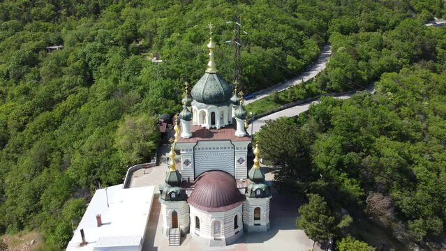 Aerial View of Foros Church and Mount road through the spring forest. Popular tourist attraction near Yalta in the Crimea. Top view Church of Holy Resurrection of Christ on Red cliff over Foros