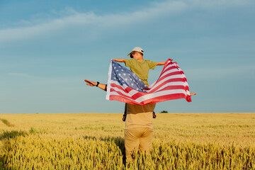 Father with son and USA flag on wheat field