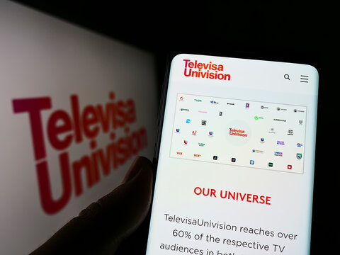 Stuttgart, Germany - 06-19-2022: Person holding cellphone with webpage of media company TelevisaUnivision Inc. on screen in front of logo. Focus on center of phone display.