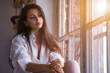Spend time at cozy home. Portrait cute sad young woman in white shirt deep thinking