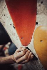 Male hands smeared with magnesium powder grabbing a hold of a climbing wall
