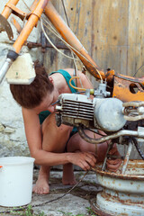 Obraz na płótnie Canvas Woman Mechanic Restoring an Old Small Motorcycle